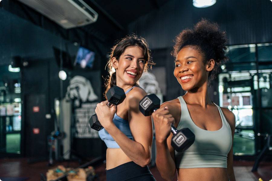 2 people with weights in a gym, looking happy. 